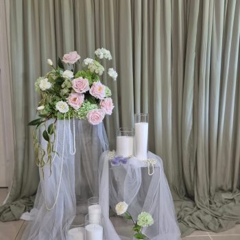 A lush corner installation of silk pink roses and white hydrangeas on a fabric backdrop for a photo booth.