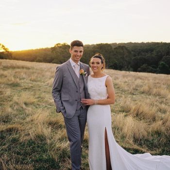 Wedding couple posing outdoors against a scenic, serene landscape backdrop.