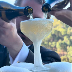 Bride and groom pouring champagne into a tower together.