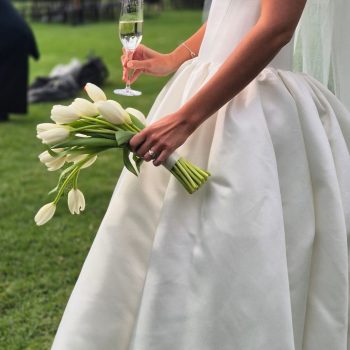 Bride holding a beautiful bouquet and champagne glass on her wedding day, elegant and candid