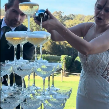 Champagne tower being poured during a wedding celebration.