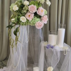 Wide angle shot of a sage and blush decorated event space featuring a floral backdrop and candles.