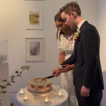 Bride and groom cutting their wedding cake together during the reception celebration.