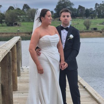 Bride and groom posing by a serene lake for wedding photos