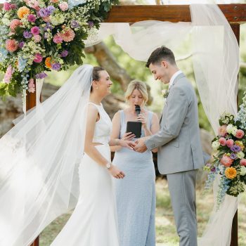 Bride and groom holding hands and exchanging wedding vows during their ceremony.