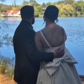 Couple posing together against a serene natural backdrop on their wedding day.