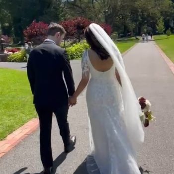 Bride and groom walking hand in hand toward the wedding venue with a romantic, scenic backdrop.