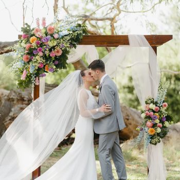 Bride and groom sharing their romantic first kiss as husband and wife at the wedding altar.