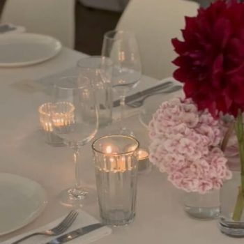 Elegant glass décor arranged on wedding reception tables with candles and floral accents.