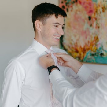 Groom adjusting his suit while preparing for the wedding day.