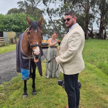 Groomsman posing with a horse outdoors during wedding festivities