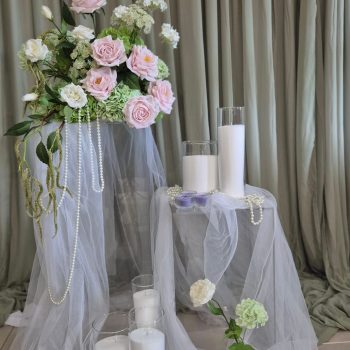 lose-up of pink roses and green hydrangeas featuring draped pearl necklaces for a shabby chic look.