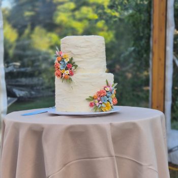Elegant wedding cake displayed on a decorated table with floral accents.